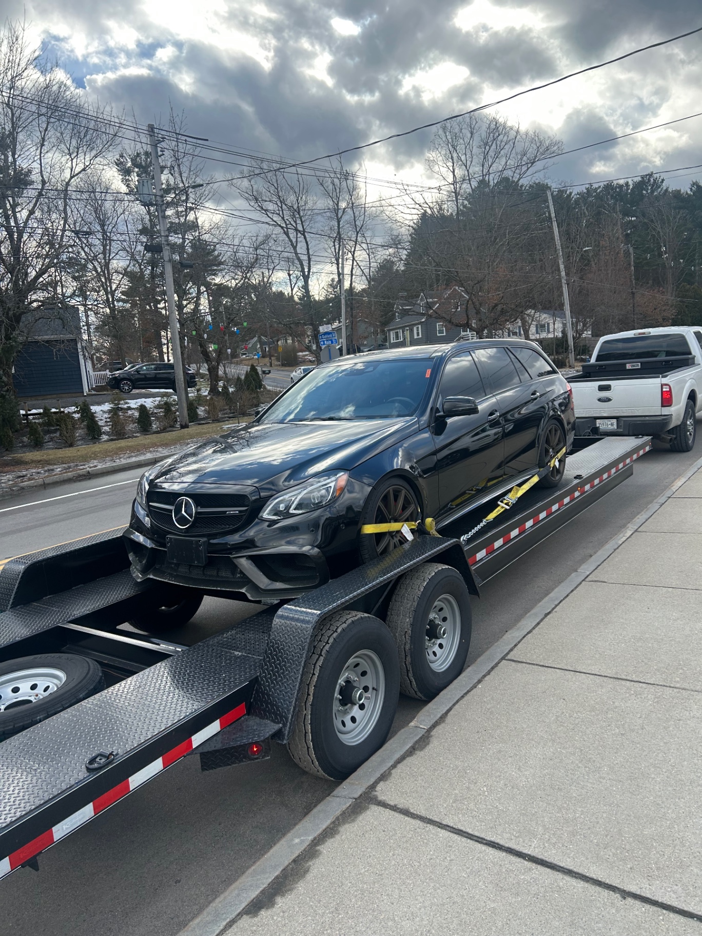 Black Mercedes-AMG wagon hauled on an enclosed-deck car trailer