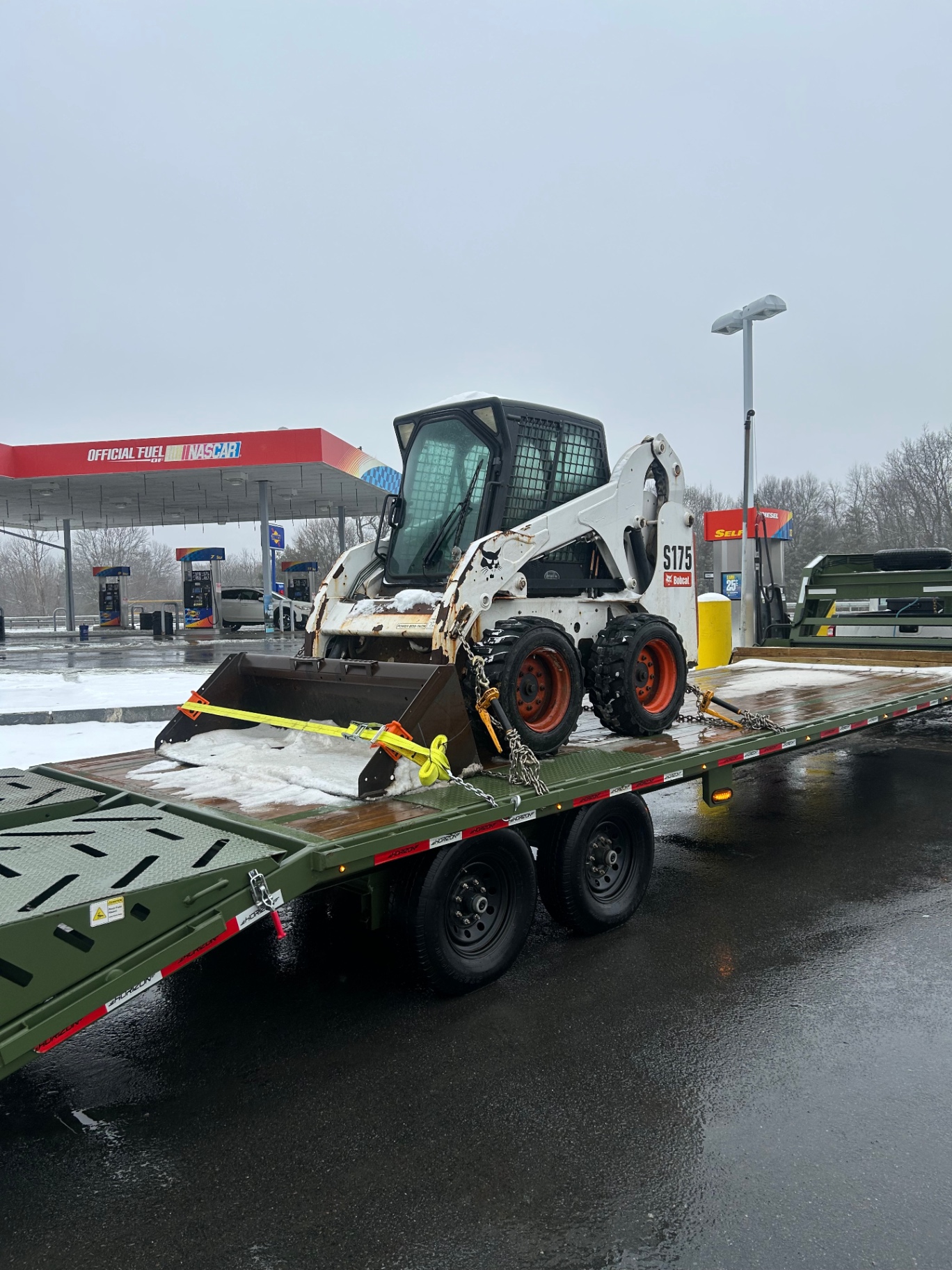 Bobcat S175 skid steer loaded at a fuel stop in transit